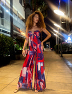 Woman in a colorful pants onesie standing on a city street at night.