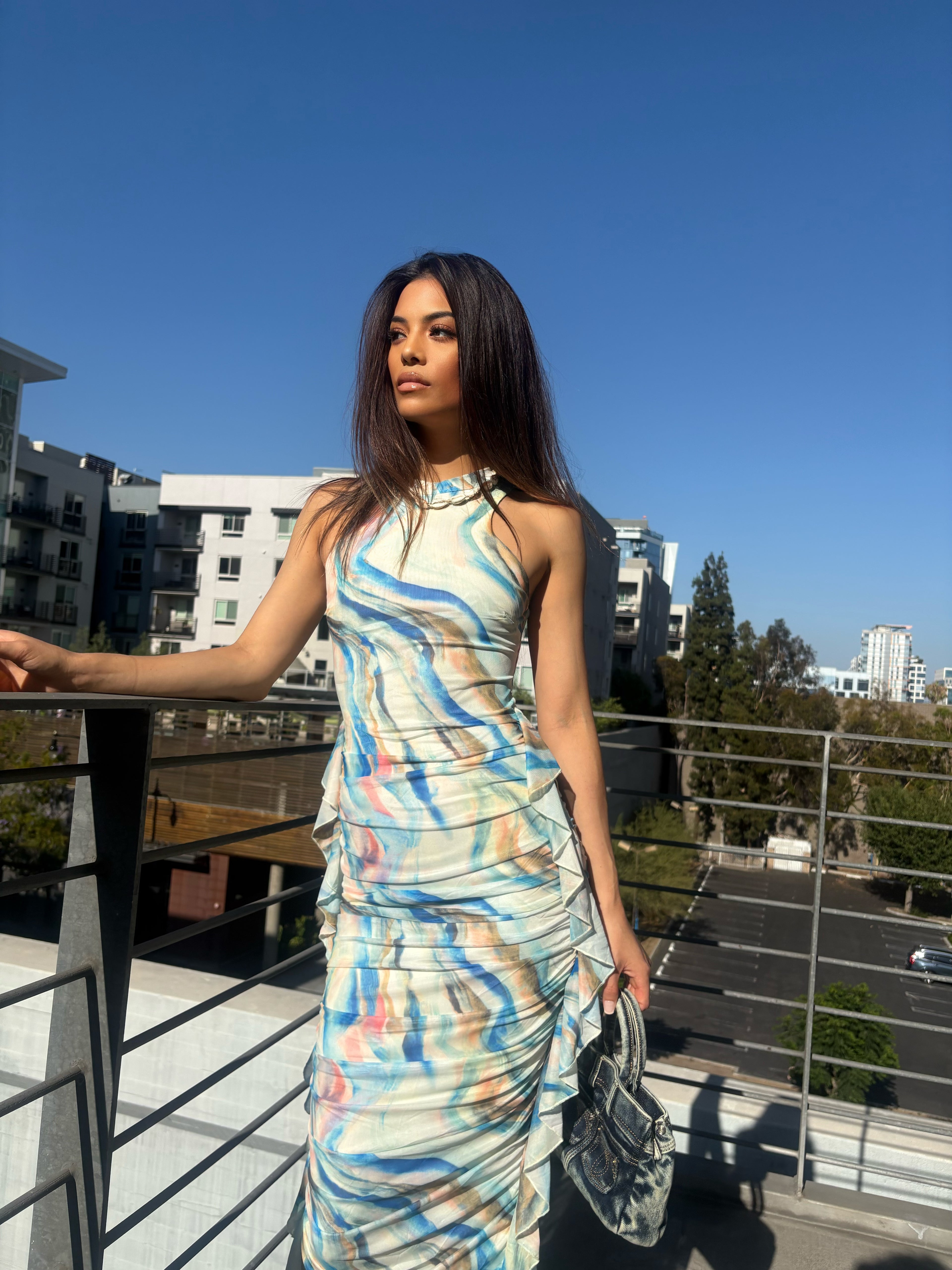 Woman in a colorful dress standing on a rooftop with buildings in the background